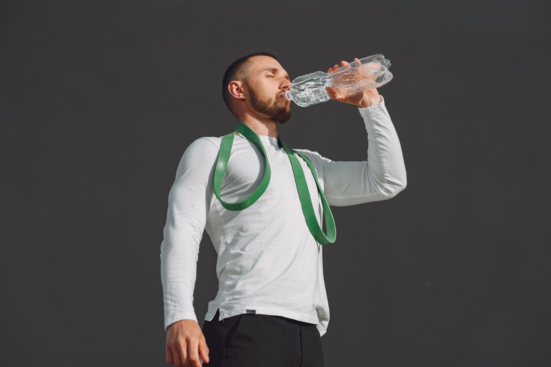 Stay Ahead Dehydration Smart Hydration — Athletic man in sportswear drinking water outdoors, promoting hydration.