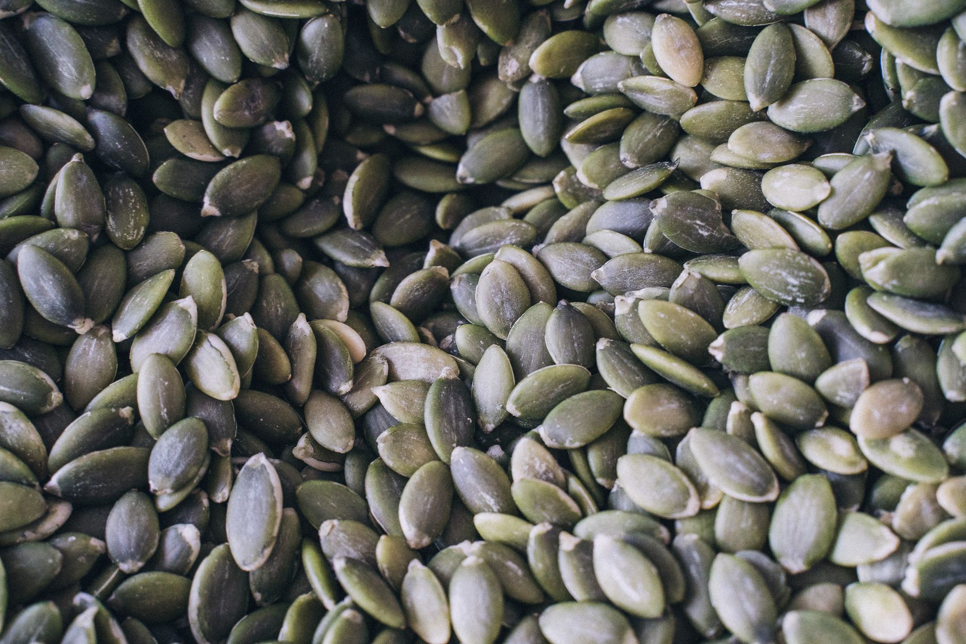 Selection of magnesium-rich foods including pumpkin seeds, dark leafy greens, almonds, and dark chocolate