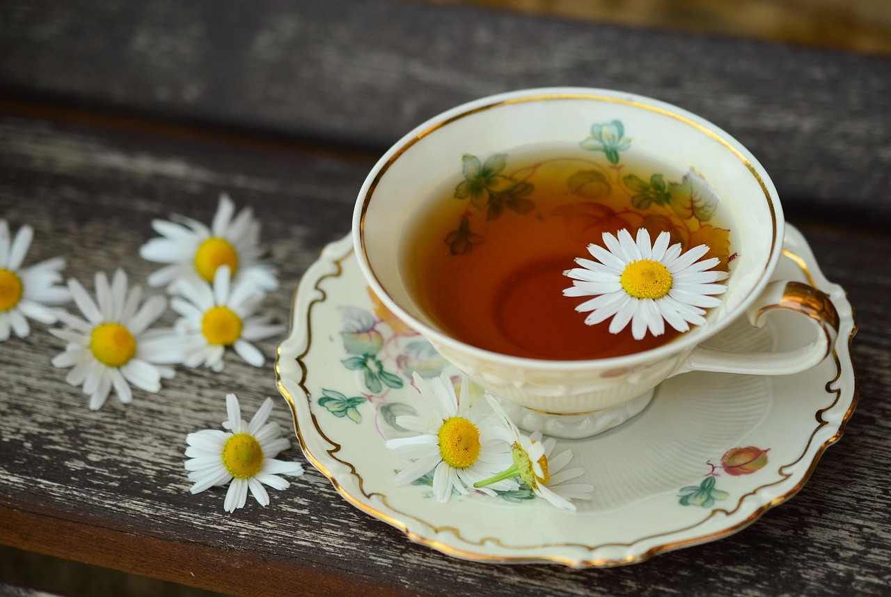 White teacup filled with chamomile tea, surrounded by dried chamomile flowers