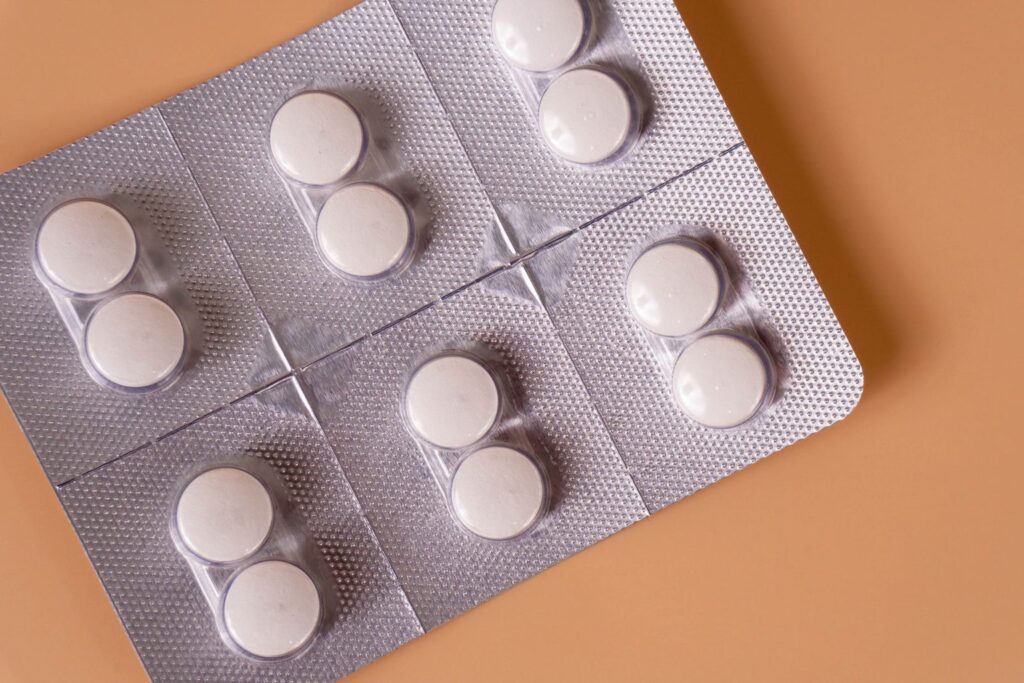 Round white tablets in a silver blister pack on a peach background