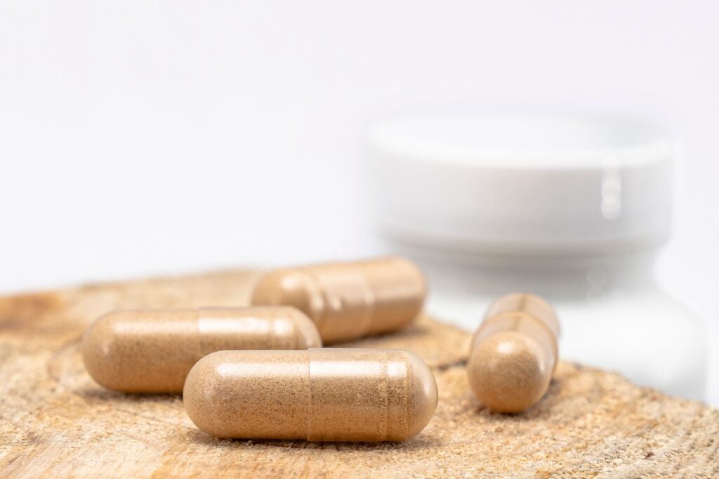 Beige berberine supplement capsules resting on a wooden surface with a bottle in the background
