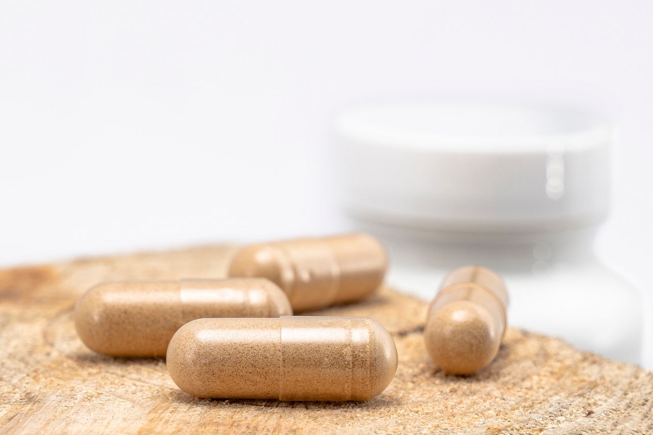 Beige berberine supplement capsules resting on a wooden surface with a bottle in the background