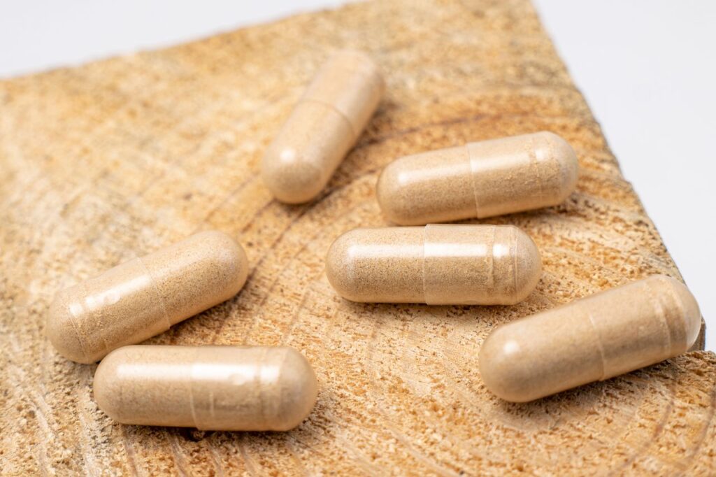 Beige supplement capsules arranged on a wooden tray