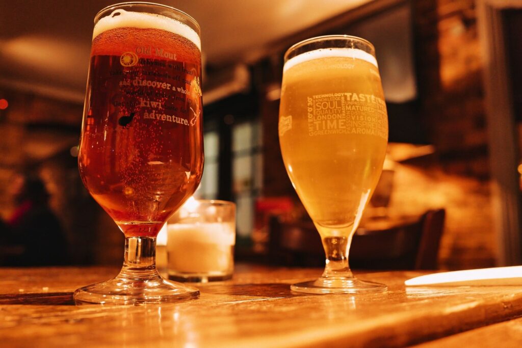 Two glasses of beer on a wooden table in a warm pub