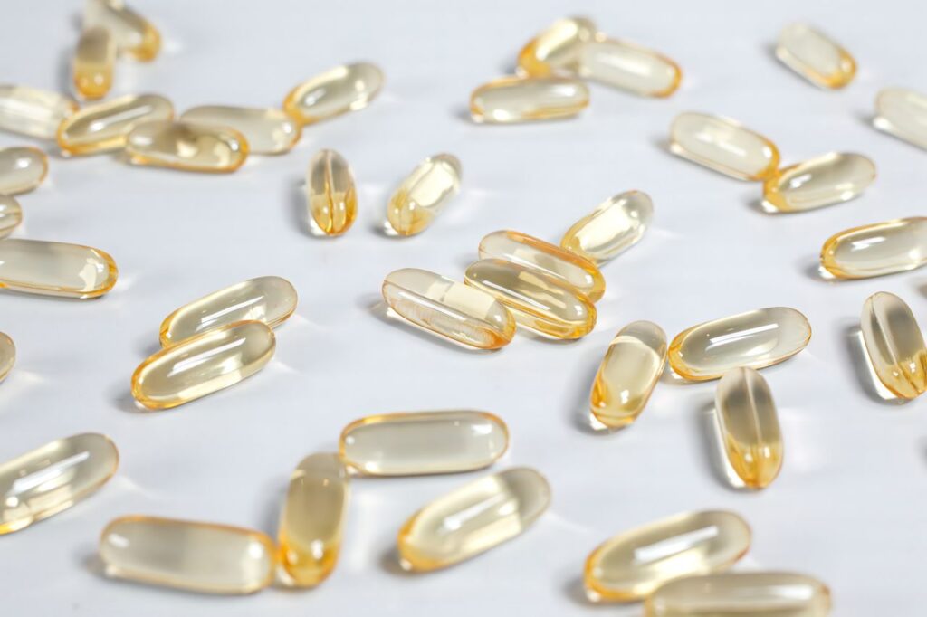 Yellow transparent softgel capsules scattered on a white background