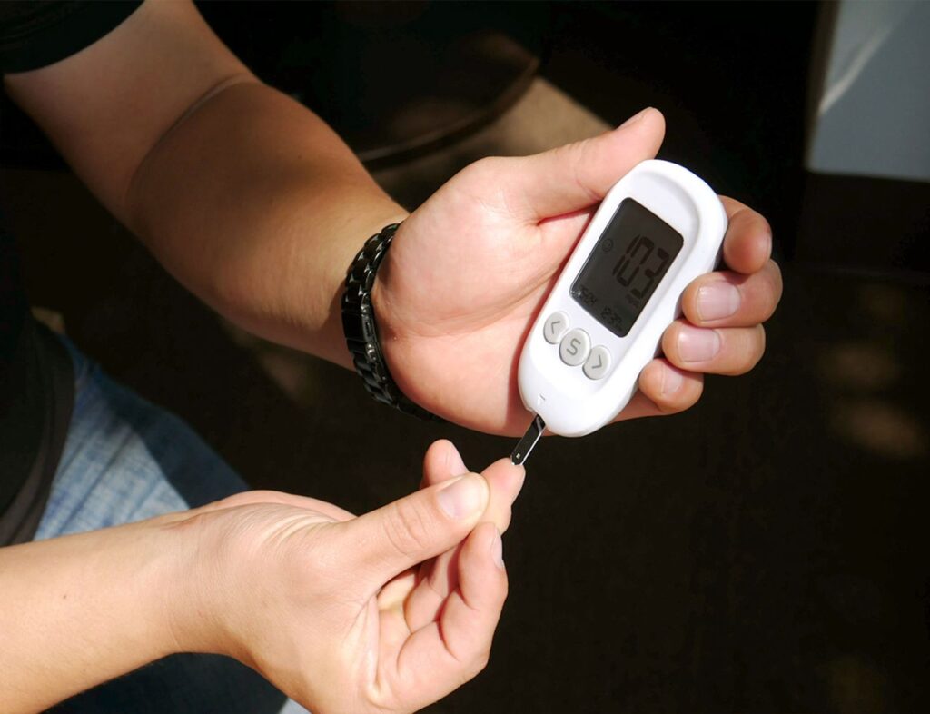 Person checking their blood sugar level with a handheld glucose meter