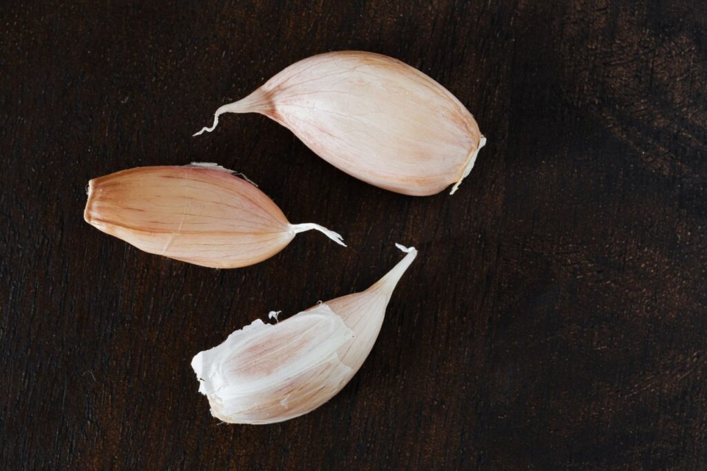 Whole fresh garlic cloves arranged on a wooden kitchen table