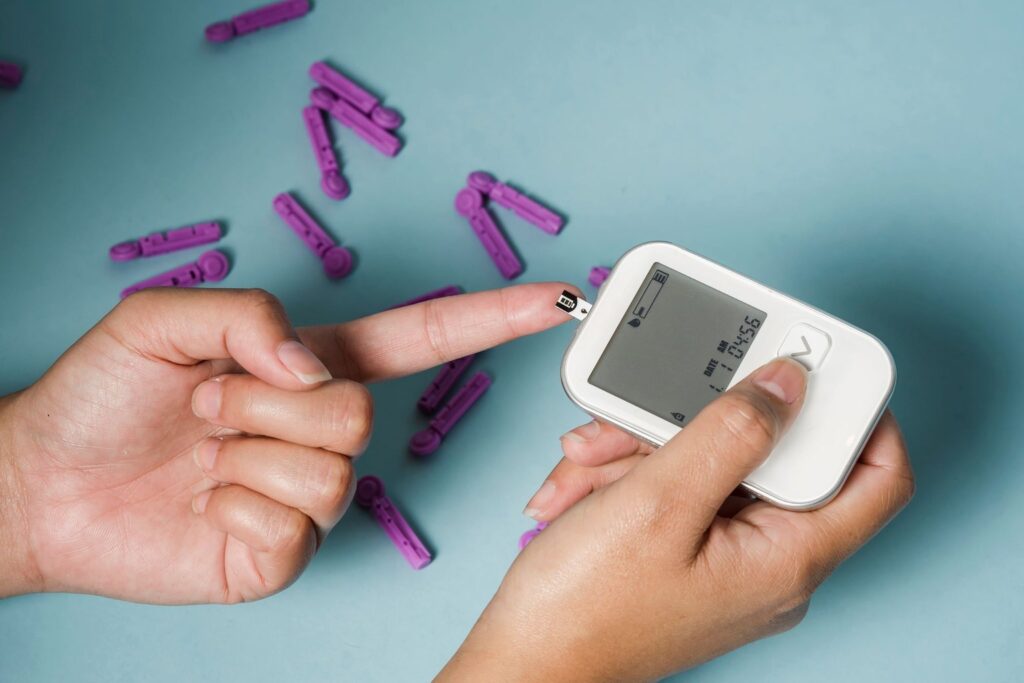 Hands using a blood glucose meter with a finger prick test