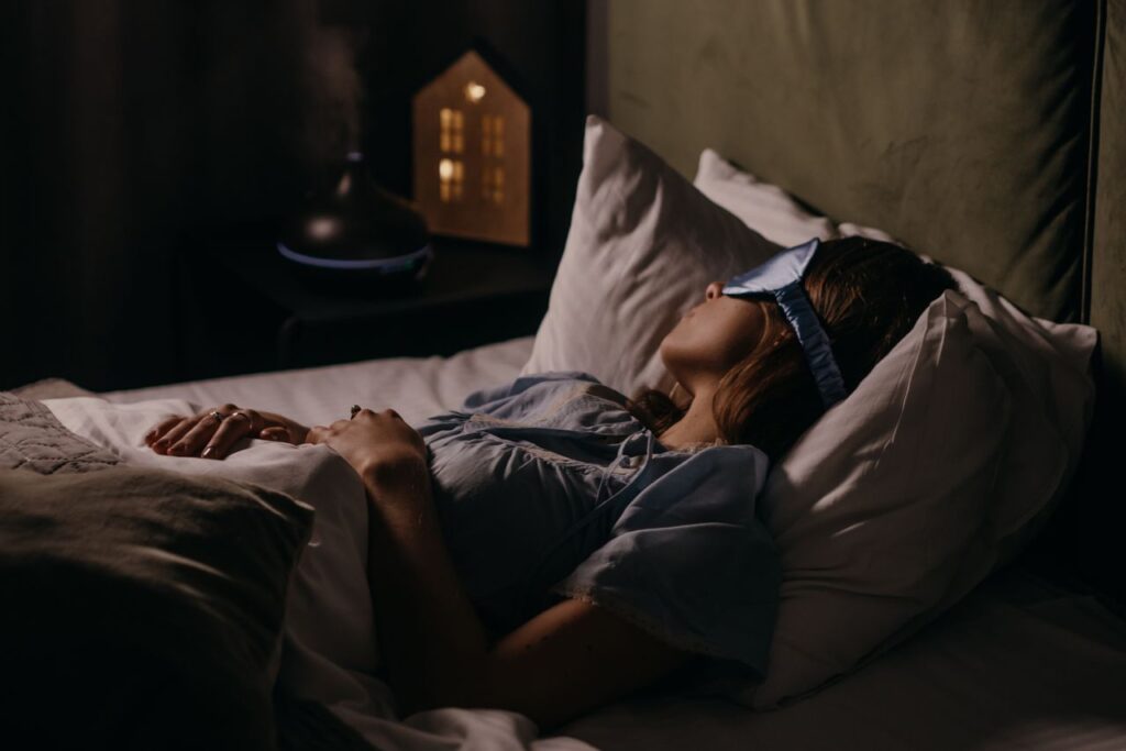 Woman asleep in a dimly lit bedroom wearing a sleep mask