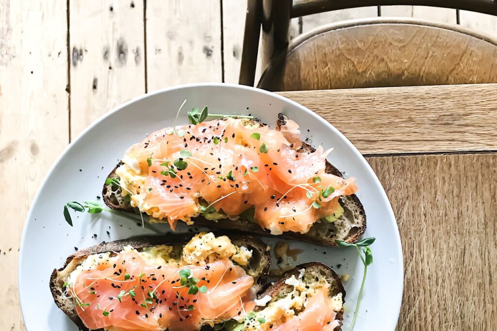 Plate of open sandwiches topped with smoked salmon and egg on a wooden table