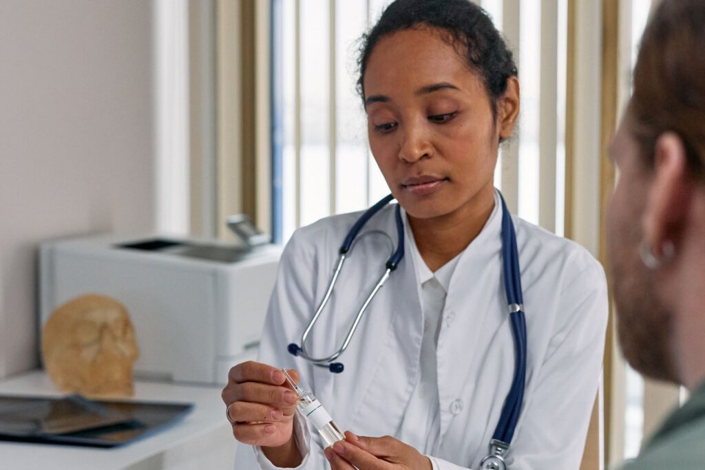 A doctor with a stethoscope talking to a patient and holding medication