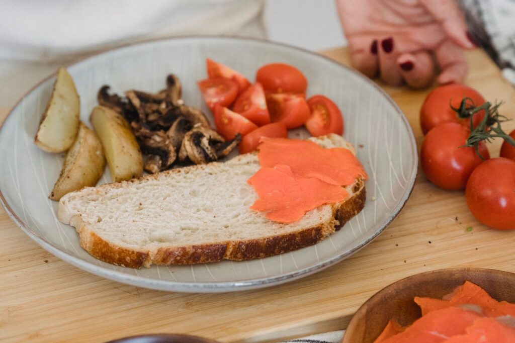 Person preparing a breakfast of eggs, smoked salmon, mushrooms and tomatoes
