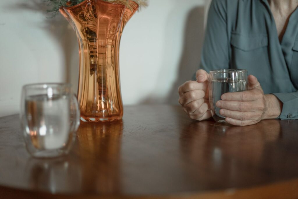 A person holding a glass of water at a wooden table