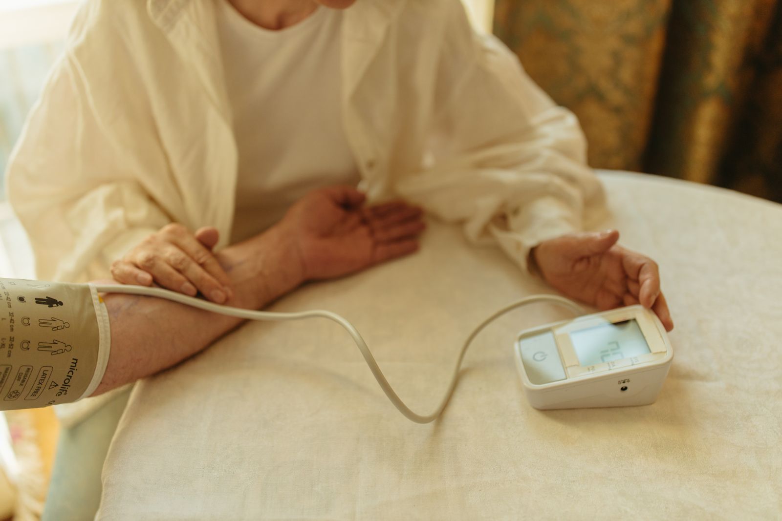 An adult checking their blood pressure at home with a digital monitor