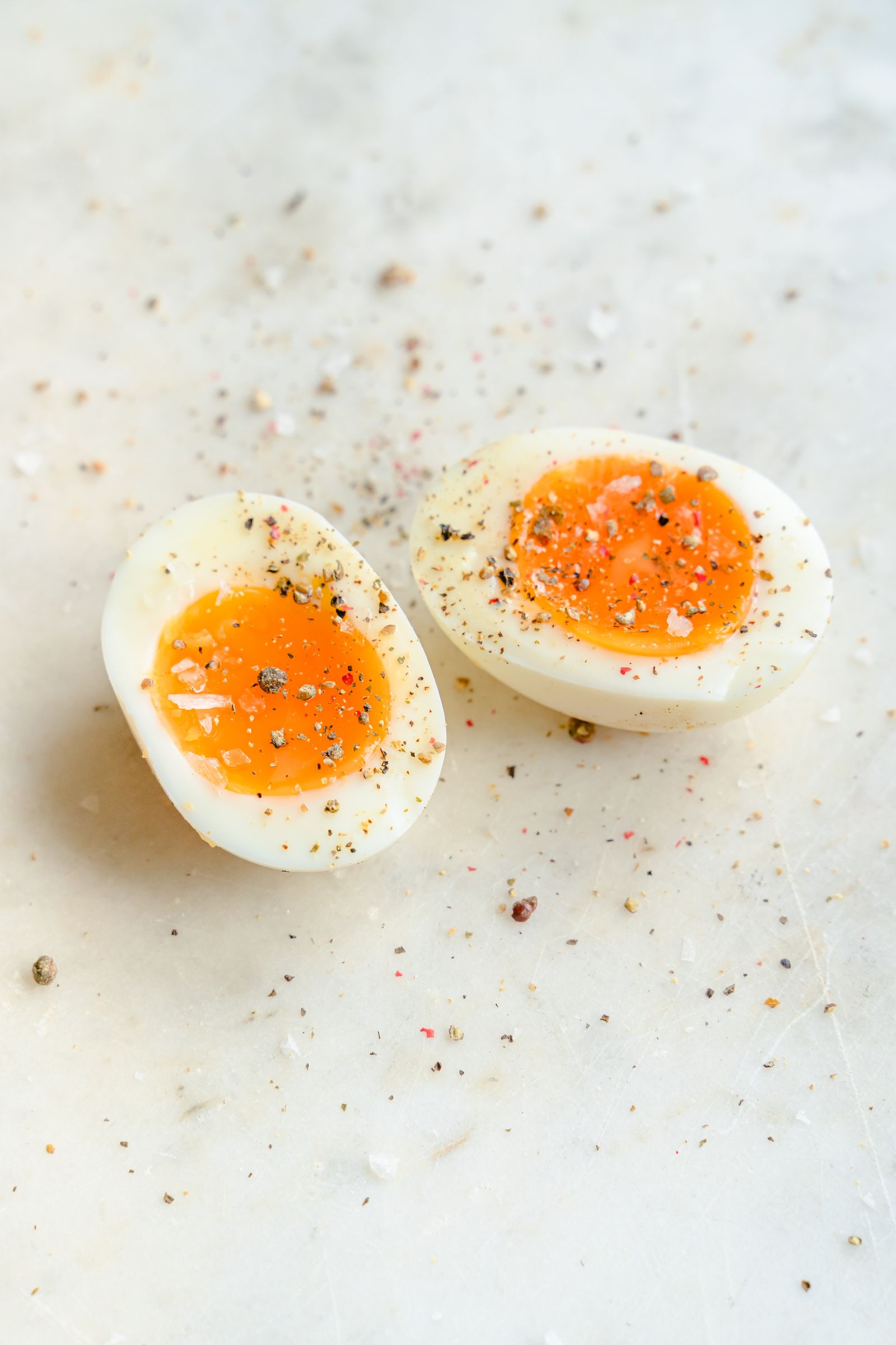 Halved boiled eggs seasoned with salt and pepper on a marble surface