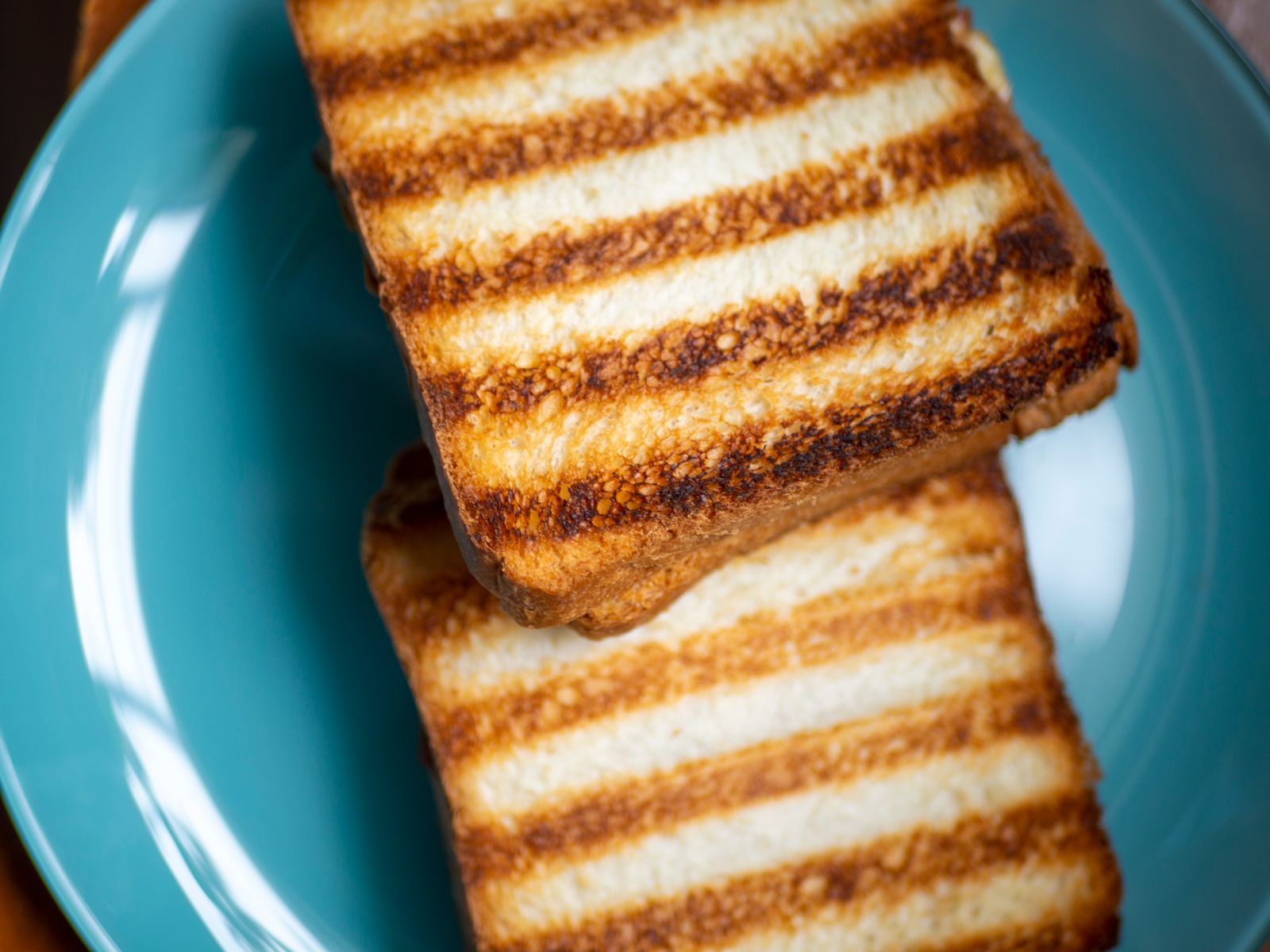 Two slices of toast on a blue plate, ready for a yeast extract spread