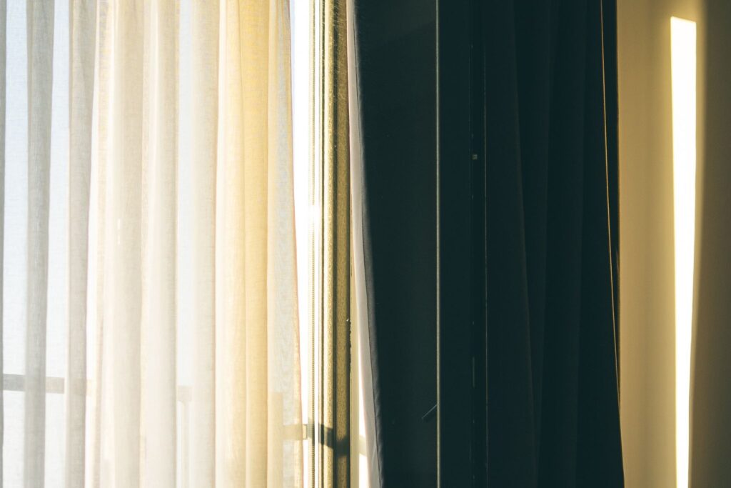 Morning light streaming through curtains into a bedroom